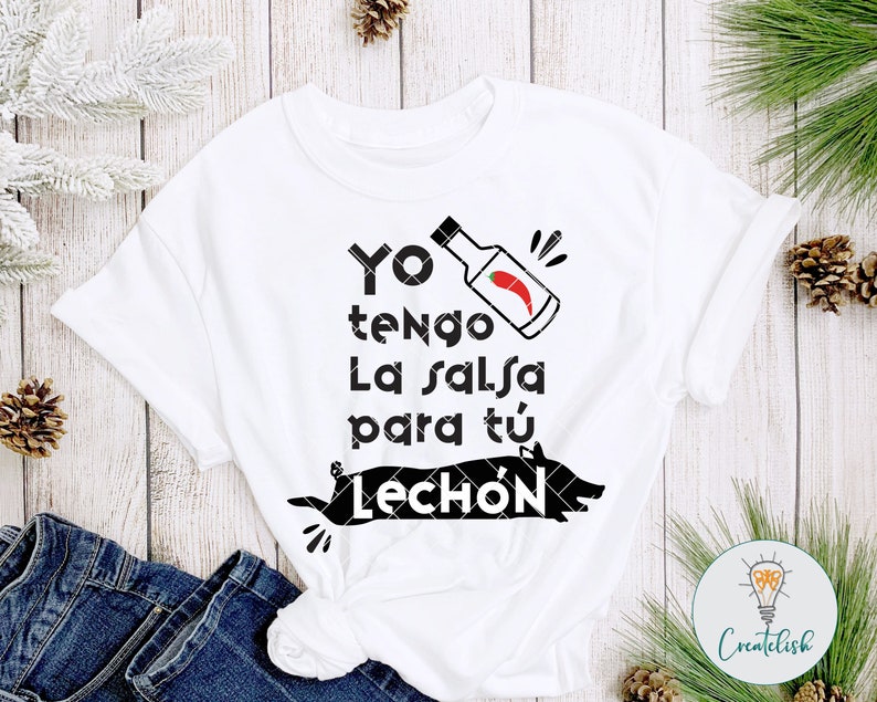 May include: White t-shirt with black text that reads "Yo tengo la salsa para t&uacute; Lech&oacute;n" with a black and white illustration of a pig and a red chili pepper in a bottle.