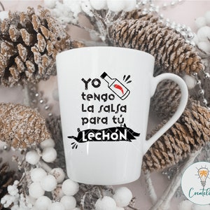 May include: White ceramic mug with a black graphic that says "Yo tengo la salsa para tu lech&oacute;n" with a red chili pepper and a red bottle of hot sauce.