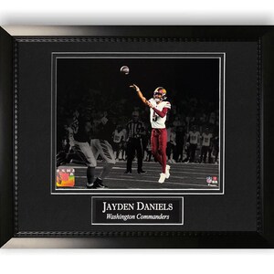 May include: Framed photograph of Jayden Daniels, Washington Commanders, throwing a football. The image is in a black frame with a white border. The text "JAYDEN DANIELS Washington Commanders" is at the bottom.