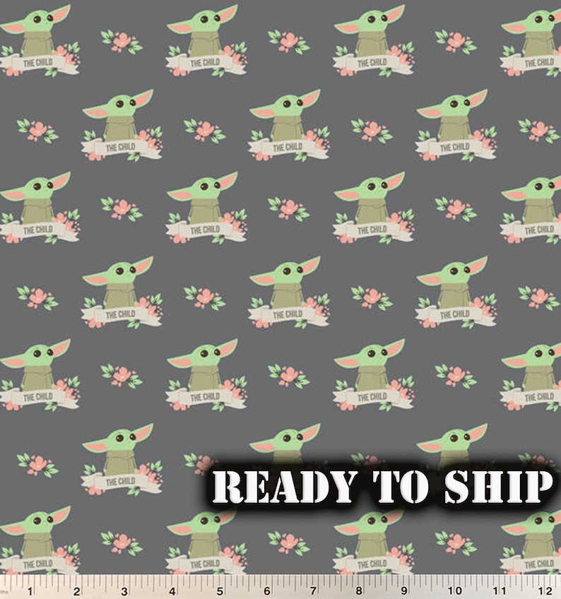 May include: A gray fabric with a repeating pattern of a green alien character with big eyes, surrounded by pink flowers and a banner that reads "The Child".