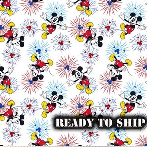 May include: White fabric with a repeating pattern of Mickey Mouse and red, white, and blue fireworks. The text "READY TO SHIP" is printed in white on a black rectangle.