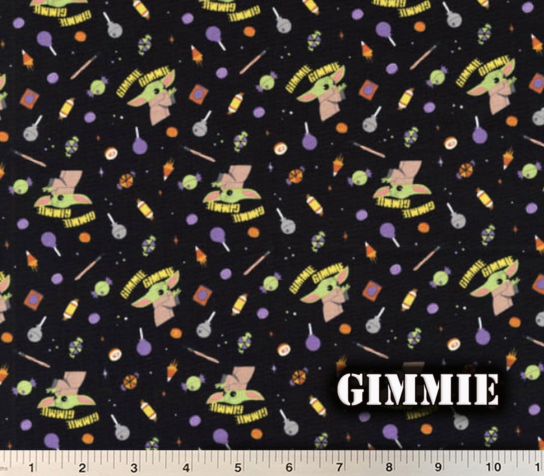 May include: Black fabric with a repeating pattern of a green alien character with the text "GIMMIE" above it. The pattern also includes candy, lollipops, and other small objects.