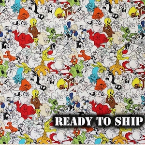 May include: White fabric with a colorful cartoon print featuring characters from Looney Tunes. The fabric is ready to ship.