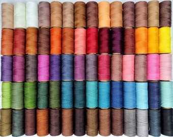 Könnte beinhalten: Eine Sammlung von 48 Spulen gewachsten Fadens in verschiedenen Farben, darunter Rot, Blau, Grün, Braun und Weiß. Die Spulen sind in Reihen auf einer weißen Oberfläche angeordnet.