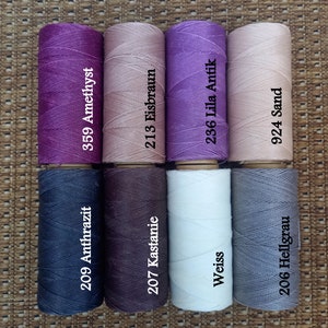Pode incluir: Oito carret&eacute;is de fio em v&aacute;rias cores, incluindo roxo, rosa, marrom, branco e cinza. Cada carretel tem um n&uacute;mero e um nome de cor impresso. Os n&uacute;meros s&atilde;o 209, 359, 207, 213, 236, 924, 206, e os nomes das cores s&atilde;o Anthrazit, Amethyst, Kastanie, Eisbraun, Lila Antik, Sand e Hellgrau.