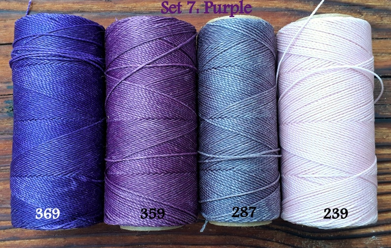 Puede incluir: Cuatro carretes de hilo de bordar en tonos de morado, azul y rosa. Los carretes est&aacute;n etiquetados con los n&uacute;meros: 369, 359, 287 y 239. El texto "Set 7: Purple" es visible en la parte superior de la imagen.