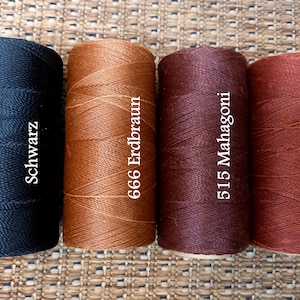 May include: Four spools of waxed thread in different colors: black, brown, burgundy, and copper. The spools are labeled with the color names and numbers: "Schwarz", "666 Erdbraun", "515 Mahagoni", and "25 Kupfer".