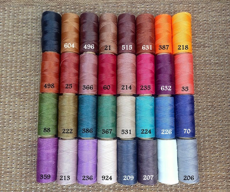 Pode incluir: Uma cole&ccedil;&atilde;o de 24 carret&eacute;is de fio encerado em v&aacute;rias cores, incluindo marrom, vermelho, verde, azul, roxo e cinza. Cada carretel &eacute; etiquetado com um n&uacute;mero.
