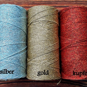 May include: Three spools of twine with metallic threads. The spools are labeled "silber", "gold", and "kupfer".