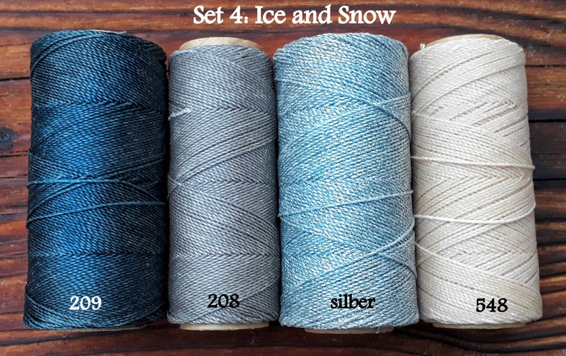 Puede incluir: Conjunto de cuatro carretes de hilo de bordar en tonos de azul, gris y blanco. Los carretes est&aacute;n etiquetados con 209, 208, silber y 548. El conjunto se titula "Set 4: Ice and Snow".