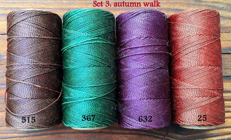 Puede incluir: Conjunto de cuatro carretes de hilo de bordar en tonos marr&oacute;n, verde, morado y rojo. Los carretes est&aacute;n etiquetados con los n&uacute;meros 515, 367, 632 y 25. El texto "Set 3. autumn walk" est&aacute; escrito encima de los carretes.