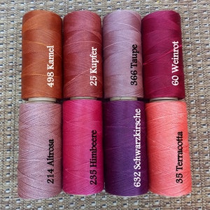 Pode incluir: Oito carret&eacute;is de fio para bordar em v&aacute;rios tons de vermelho, rosa e marrom. Os carret&eacute;is s&atilde;o etiquetados com n&uacute;meros e nomes alem&atilde;es para as cores, incluindo "Altrosa", "Kamel", "Himbeere", "Kupfer", "Schwarzkirsche", "Taupe", "Weinrot" e "Terracotta".