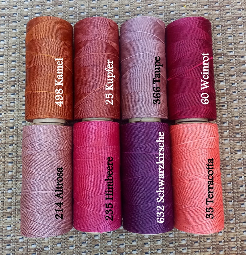 Pode incluir: Oito carret&eacute;is de fio para bordar em v&aacute;rios tons de vermelho, rosa e marrom. Os carret&eacute;is s&atilde;o etiquetados com n&uacute;meros e nomes alem&atilde;es para as cores, incluindo "Altrosa", "Kamel", "Himbeere", "Kupfer", "Schwarzkirsche", "Taupe", "Weinrot" e "Terracotta".