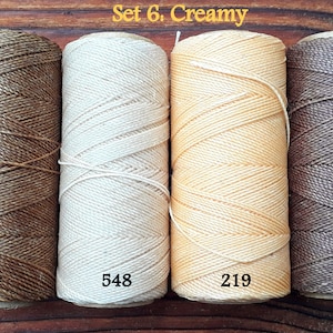 Puede incluir: Conjunto de cuatro carretes de hilo de lino encerado en tonos de marr&oacute;n, beige y crema. Los carretes est&aacute;n etiquetados con los n&uacute;meros 604, 548, 219 y 362. El texto "Set 6. Creamy" se muestra sobre los carretes.