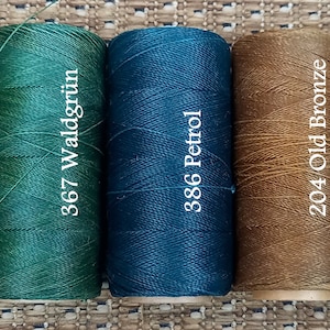 May include: Five spools of waxed thread in different colors. The spools are labeled with numbers and color names: 88 Olive, 367 Waldgr&uuml;n, 386 Petrol, 204 Old Bronze, and 211 Holz.