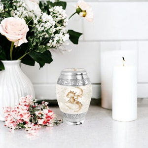Keepsake baby dragon urn elegantly displayed with flowers, offering a beautiful and unique way to remember a loved one. Ideal for small portions of ashes.