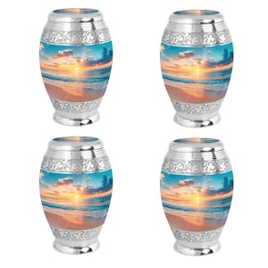 May include: Four silver urns with a beach sunset scene printed on the front. The urns have an ornate design around the top and bottom.