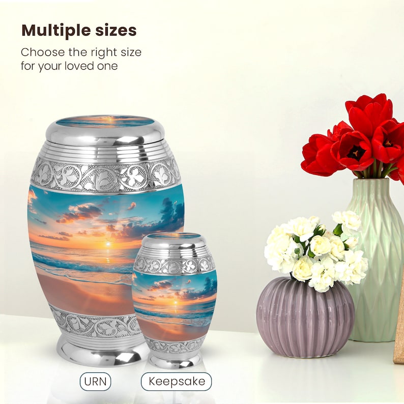 May include: Two silver metal urns with a beach sunset image. The larger urn is labeled "URN" and the smaller urn is labeled "Keepsake".