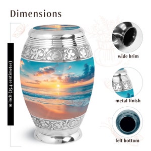 May include: Silver cremation urn with a beach sunset scene. The urn is 10 inches (25.4 centimeters) tall and has a wide brim, metal finish, and felt bottom.