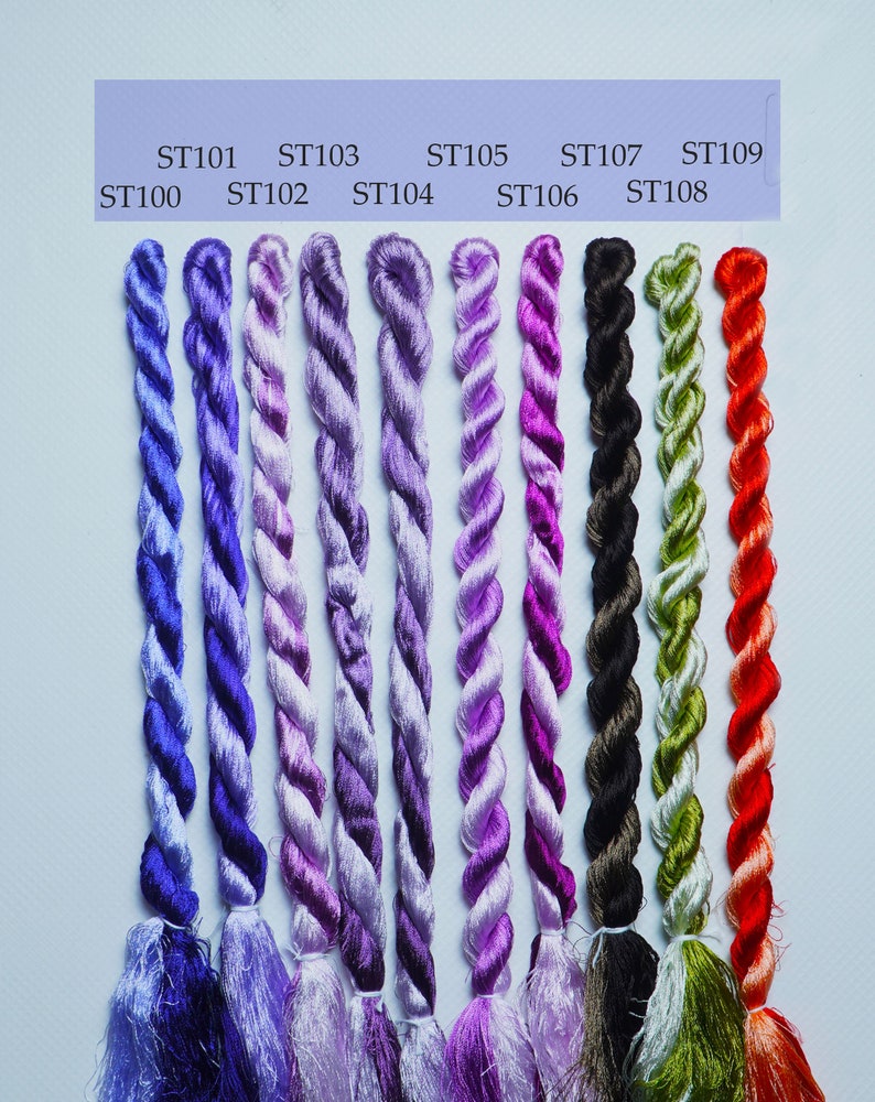 May include: Nine spools of embroidery floss in various shades of purple, green, black, and red. The spools are labeled with the numbers ST100 through ST109.