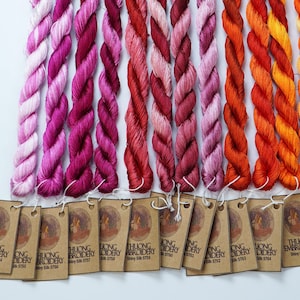 May include: A collection of 14 skeins of embroidery floss in shades of pink, red, orange, and yellow. Each skein is labeled with "THUONG EMBROIDERY" and a unique number.