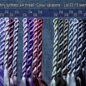 May include: Fifteen skeins of shiny synthetic silk thread in various shades of purple, gray, and blue. The skeins are arranged in rows, with each row labeled with a number and letter combination, such as ST39, ST40, ST41, etc.