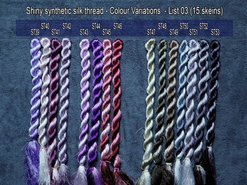 May include: Fifteen skeins of shiny synthetic silk thread in various shades of purple, gray, and blue. The skeins are arranged in rows, with each row labeled with a number and letter combination, such as ST39, ST40, ST41, etc.