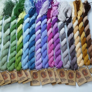May include: A collection of 14 skeins of hand-dyed embroidery floss in various shades of green, blue, purple, gray, beige, and brown. Each skein is labeled "Thung Embroidery Cotton 120m".