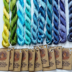 May include: A collection of 10 skeins of embroidery floss in shades of yellow, green, blue, and purple. Each skein is labeled with the brand name "Thuong Embroidery" and a unique product code.