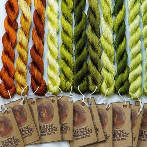 May include: A set of 10 spools of embroidery floss in shades of orange, yellow, and green. The floss is labeled "THUONG EMBROIDERY" and has a silk sheen.