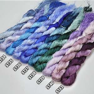May include: A collection of 10 skeins of embroidery floss in various shades of blue, green, and purple. The skeins are labeled with the numbers ST32, ST33, ST34, ST35, ST36, ST37, ST38, ST39, ST40, and ST41.
