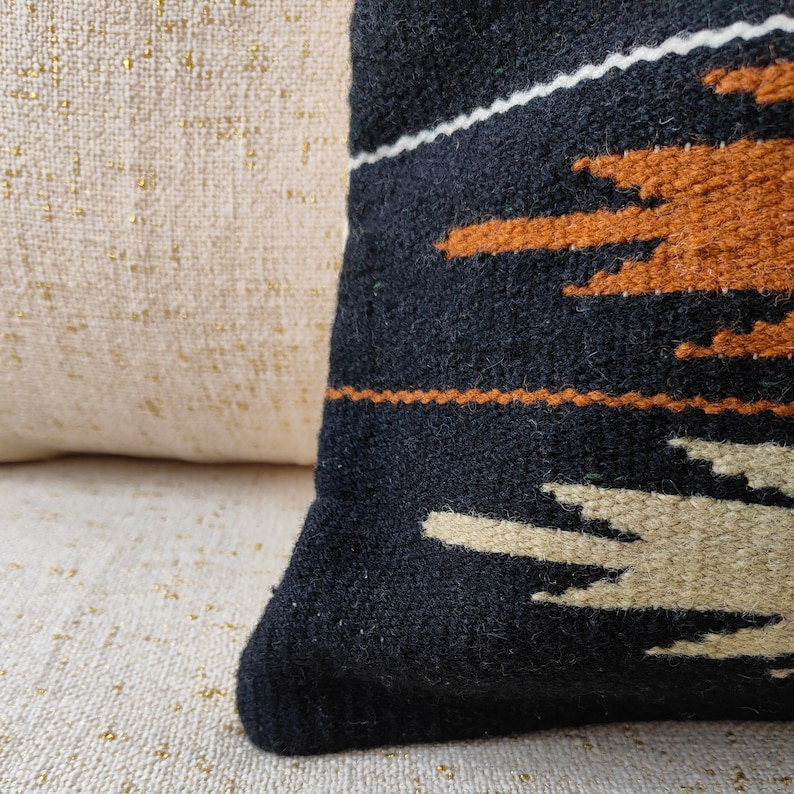 May include: Black throw pillow with a geometric pattern in beige, brown, and white. The pillow is made of a woven fabric and has a soft, textured feel.
