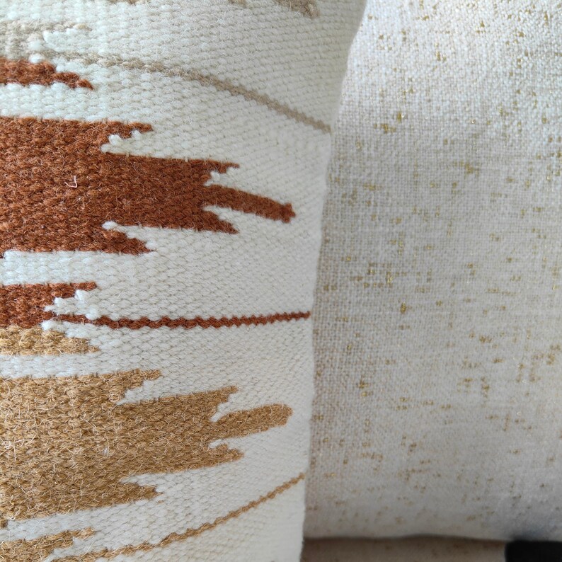 May include: Two white throw pillows with different textures. One pillow has a woven pattern with brown and beige stripes. The other pillow has a smooth, slightly textured surface.
