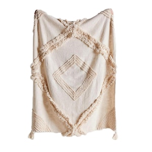 May include: A cream-colored throw blanket with a diamond pattern and fringe trim. The blanket is made of a soft, textured fabric.