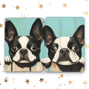 May include: Two black and white Boston Terrier dogs peeking over a wooden fence. The dogs have brown eyes and are looking directly at the viewer. The background is a light blue color.