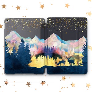 Puede incluir: Una funda para iPad azul oscuro y dorada con una escena de montaña de acuarela y dos siluetas de ciervos. El fondo presenta un cielo estrellado.