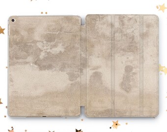 May include: A beige iPad case with a textured, marbled design. The case is closed and has a flap that folds over the front of the iPad.