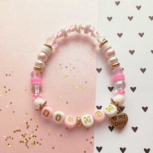 May include: Pink and white beaded bracelet with gold letter beads spelling "DOG MOM" and a gold charm that says "my dog".