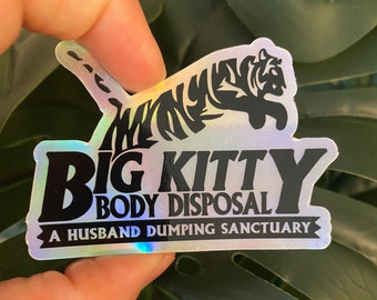 以下が含まれることがあります： 黒い虎のシルエットと「Big Kitty Body Disposal A Husband Dumping Sanctuary」というテキストが書かれたホログラフィックステッカーです。