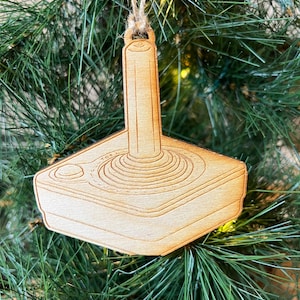 May include: A wooden Christmas tree decoration shaped like a vintage joystick. The ornament is brown and features a detailed design.