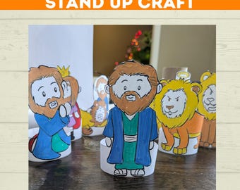 May include: A stand-up craft featuring Daniel in the lion's den. The image shows several cartoon figures, including Daniel and lions, with the text "DANIEL IN LION'S DEN STAND UP CRAFT" at the top. The figures are colorful and designed to stand upright.