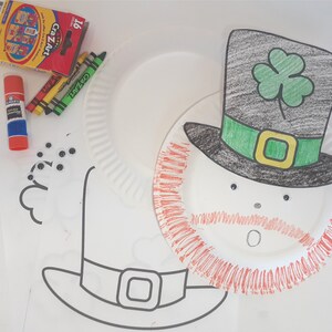 May include: A paper plate craft project to make a leprechaun. The paper plate is decorated with red, green, and black markers. The leprechaun has a black hat with a green shamrock on top, a green band around the hat, and a red beard. The leprechaun has googly eyes and a white mouth.