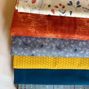 May include: Stack of six fabric swatches in various colors and patterns. The top swatch is white with a floral pattern, the second is orange with a textured pattern, the third is blue with a floral pattern, the fourth is yellow with white polka dots, the fifth is teal blue, and the bottom swatch is light blue with a striped pattern.