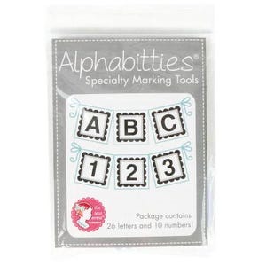 May include: A set of black and white alphabet and number stamps with scalloped edges. The stamps are arranged in a banner shape and are labeled "ABC" and "123". The package contains 26 letters and 10 numbers.