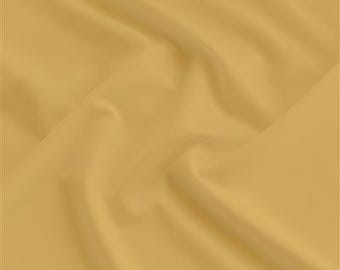 May include: A close-up shot of a golden-yellow fabric with soft folds and subtle shadows. The material appears smooth and possibly lightweight, suggesting it could be used for clothing or home decor.