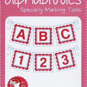 May include: A set of red and white alphabet and number stencils for marking fabric. The stencils are shaped like banners and feature a scalloped edge. The text on the image reads "Alphabitties Specialty Marking Tools" and "Package contains 26 letters and 10 numbers!"
