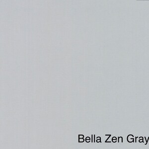 May include: A solid, light gray fabric with a subtle texture. The text "Bella Zen Gray" is displayed in a black, sans-serif font at the bottom of the image. The fabric appears to be a neutral color.