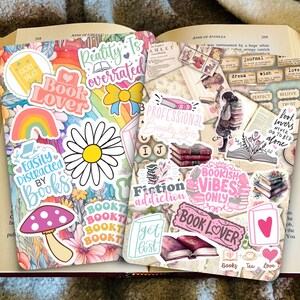 May include: A collection of colourful book-themed stickers with phrases like "Book Lover", "Bookish Vibes Only", "Reality is overrated", and "Fiction Addiction".
