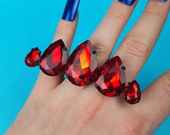 May include: A set of four red gemstone rings with black metal settings. The rings are designed to be worn on multiple fingers.