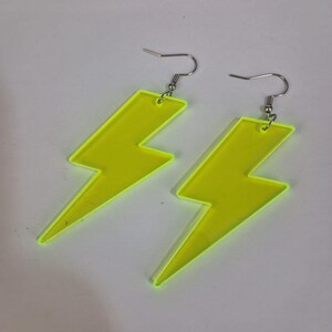 Puede incluir: Un par de pendientes de rayo de acrílico amarillo neón. Cada pendiente tiene un gancho para la oreja de color plateado. Un accesorio brillante y llamativo.